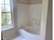 Clean bathroom featuring a bright window, tiled walls, and a large tub for relaxing baths at 4616 Silverdene St, Raleigh, NC 27616