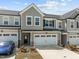 Beautifully designed townhome with two-car garage, stone accents, and grey vertical siding at 486 Autumn Rain St, Cary, NC 27519