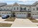 Charming townhome featuring a two-car garage, grey siding, and beautifully manicured landscaping at 486 Autumn Rain St, Cary, NC 27519