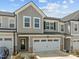 Beautifully designed townhome with two-car garage, stone accents, and grey vertical siding at 486 Autumn Rain St, Cary, NC 27519
