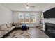 Bright living room featuring a comfortable sofa, a large window, a fireplace, and a stylish leaf patterned rug at 486 Autumn Rain St, Cary, NC 27519