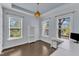 Bright bedroom featuring hardwood floors, large windows, and a modern light fixture at 8121 Greys Landing Way, Raleigh, NC 27615