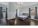 A large bedroom with hardwood floors and a modern light fixture and dark grey curtains at 8121 Greys Landing Way, Raleigh, NC 27615