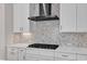 Modern kitchen with white cabinets, mosaic backsplash, stainless hood, and a black gas cooktop at 8121 Greys Landing Way, Raleigh, NC 27615