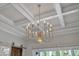 A modern multi-bulb chandelier hangs from a coffered ceiling in this living space at 8121 Greys Landing Way, Raleigh, NC 27615