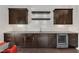 Modern wet bar area featuring dark cabinets, wine cooler, granite countertop, and floating shelves at 8121 Greys Landing Way, Raleigh, NC 27615