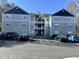 Three story condo building with covered entrance, multiple balconies, and ample parking space on a sunny day at 1140 Carlton Ave # 201, Raleigh, NC 27606