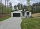 Modern home exterior featuring a black garage door, contemporary design, and a spacious driveway at 124 Horseman Dr, Louisburg, NC 27549