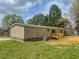 Backyard view showcasing the home's rear facade with a wooden deck, grassy area, and exterior utilities at 1326 Stephens Dr, Roxboro, NC 27573