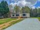 Welcoming one-story home with a gravel driveway and green lawn and surrounded by lush trees at 1326 Stephens Dr, Roxboro, NC 27573