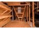 Unfinished attic with wooden beams, a small window, storage shelves, and exposed pipes at 135 Brocks Trce, Burlington, NC 27215