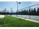 Outdoor tennis court featuring a black chainlink fence, green surface, and surrounded by trees and grass at 135 Brocks Trce, Burlington, NC 27215