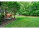 Lush backyard with a well-manicured lawn, mature trees, and a charming playhouse for outdoor fun at 1404 Rhea Dr, Garner, NC 27529