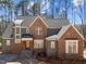 New two-story home with mixed brick and gray siding, dark roof, and a charming covered front porch at 1425 Lake Adventure Ct, Raleigh, NC 27613