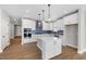 Bright kitchen featuring white cabinets, stainless steel appliances, island, and sleek pendant lighting at 1801 Angelonia Way, Fuquay Varina, NC 27526