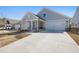 A single-story home displaying a large driveway, two-car garage, and an inviting covered porch at 1805 Angelonia Way, Fuquay Varina, NC 27526