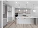 A modern kitchen is equipped with stainless steel appliances, an island, and gray cabinetry at 1805 Angelonia Way, Fuquay Varina, NC 27526