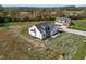 An aerial view of a modern farmhouse-style home with dark roof and white siding with an expansive lawn and detached garage at 1886 Mays Crossroad Rd, Louisburg, NC 27549