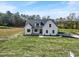 Aerial of a modern farmhouse with black roof, white siding, and a well-manicured lawn at 1886 Mays Crossroad Rd, Louisburg, NC 27549