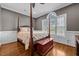 Bedroom with four-poster bed, hardwood floors, trim, and a large window at 2011 Gibsonville Ossipee Rd, Elon, NC 27244