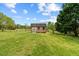 Rustic storage shed in backyard is great for extra space, flanked by green grass and blue skies at 2011 Gibsonville Ossipee Rd, Elon, NC 27244
