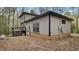 Rear exterior view featuring a gray home with a deck, brick foundation, and wooded surroundings at 206 Rocky Hills Rd, Pittsboro, NC 27312