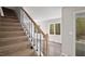 Carpeted stairway with wood railing and a view of the rear deck through the windows at 206 Rocky Hills Rd, Pittsboro, NC 27312
