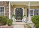 Welcoming front porch with decorative plants, a security system sign, and a stylish front door at 2223 Lazy River Dr, Raleigh, NC 27610