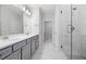 Bright bathroom with double sink vanity, glass shower door, and marble look tile at 2304 Beeblossom Pl, Fuquay Varina, NC 27526