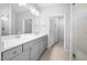 Modern bathroom with dual sinks, vanity, large mirror, walk-in shower, and doorway leading to the walk-in closet at 2316 Beeblossom Pl, Fuquay Varina, NC 27526