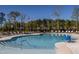 Inviting community pool with sun loungers and umbrellas surrounded by lush trees under a clear blue sky at 2316 Beeblossom Pl, Fuquay Varina, NC 27526