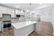 Bright, open kitchen features white cabinets, stainless appliances, large island, and modern pendant lighting at 2316 Beeblossom Pl, Fuquay Varina, NC 27526