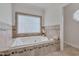 Elegant bathtub with tile surround and window, perfect for relaxation and enjoying the natural light at 2411 Lynch Store Rd, Mebane, NC 27302