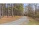 Peaceful gravel driveway surrounded by tall trees, creating a private and natural entrance to the property at 2411 Lynch Store Rd, Mebane, NC 27302