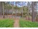 A charming wooden gate leads to a picturesque pond surrounded by lush greenery and mature trees at 2411 Lynch Store Rd, Mebane, NC 27302