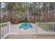 A backyard pool surrounded by tall trees as seen from a wooden deck with white railings and stairs at 2411 Lynch Store Rd, Mebane, NC 27302