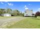 Side view of the white home with a gray outbuilding and a large yard with a wooded area at 2651 Bennett Rd, Creedmoor, NC 27522