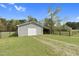 Gray outbuilding with a white door, gravel driveway, and fencing at 2651 Bennett Rd, Creedmoor, NC 27522