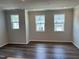 Bright living room featuring a dark floor, neutral walls, and three large windows for plenty of natural light at 331 Deercroft Dr, Apex, NC 27539
