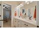 Bathroom with double sinks, a framed mirror, white cabinets, and a view to another bedroom in the background at 36 Wellspring Cir, Clayton, NC 27527