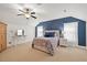 Bright bedroom featuring a ceiling fan, a large bed, and natural light streaming through the white-curtained windows at 36 Wellspring Cir, Clayton, NC 27527