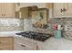 Close up of gas range cooktop with stone backsplash and stylish accents at 36 Wellspring Cir, Clayton, NC 27527