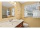 Bathroom with a large mirror, wood vanity, and window for natural light at 5401 Kaplan Dr, Raleigh, NC 27606