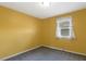 A cozy bedroom with yellow walls featuring a window with lace curtains for natural light at 5401 Kaplan Dr, Raleigh, NC 27606