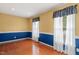 Well-lit living room with hardwood floors, blue and beige wainscoting, and large windows with white curtains at 5401 Kaplan Dr, Raleigh, NC 27606