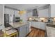 Open kitchen with granite countertops, gray island with seating, and stainless-steel appliances at 6 S Summerhill Rdg, Clayton, NC 27520
