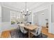 Elegant dining room with hardwood floors, large windows, modern chandelier, and stylish furniture for entertaining at 609 Meyers Place Ln, Holly Springs, NC 27540