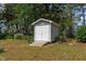 A well-maintained storage shed with double doors and a ramp in a wooded backyard at 664 Marler Rd, Benson, NC 27504