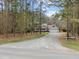 Exterior view of the property with a long gravel driveway, well-kept lawn, and surrounded by lush trees at 707 Sinai Cir, Hillsborough, NC 27278