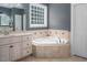 En suite bathroom featuring a soaking tub, large window, vanity, and tiled accents at 711 Kentcie Ln, Efland, NC 27243
